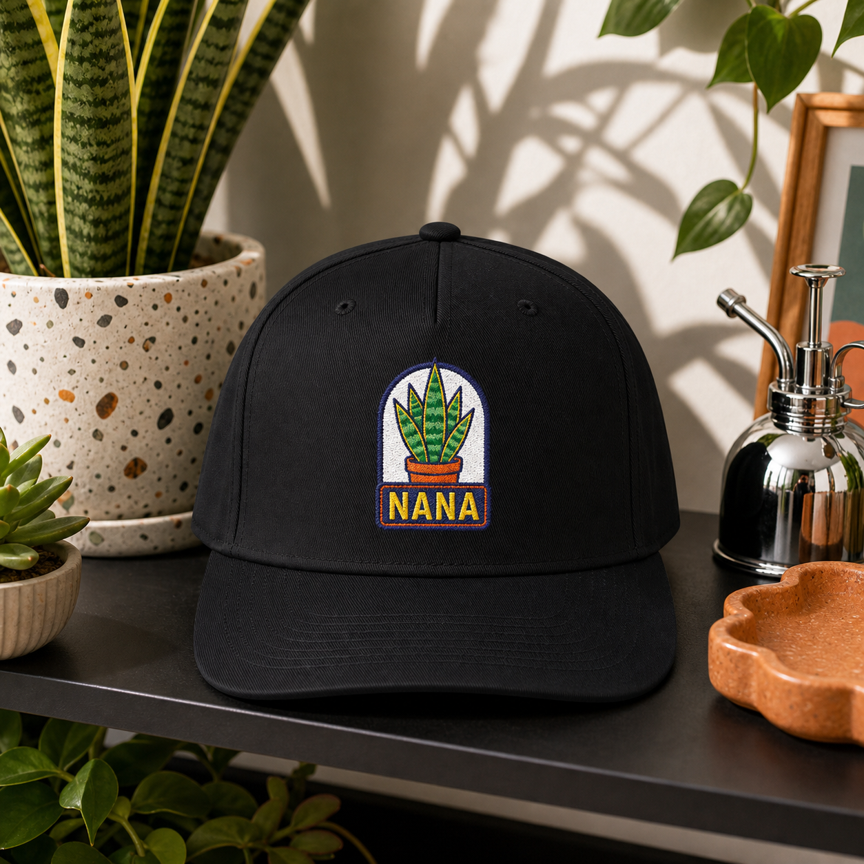 Nana Snake Plant embroidered hat in Black on a modern plant shelf